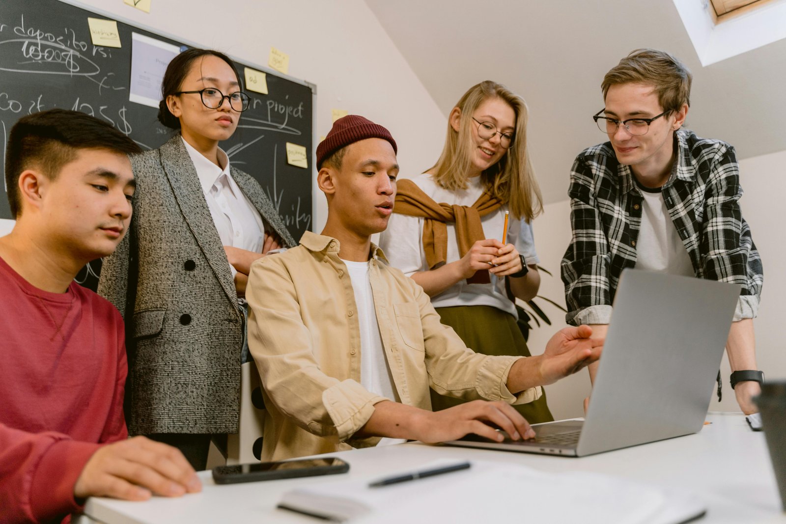 Group of young adults looking at the same laptop screen