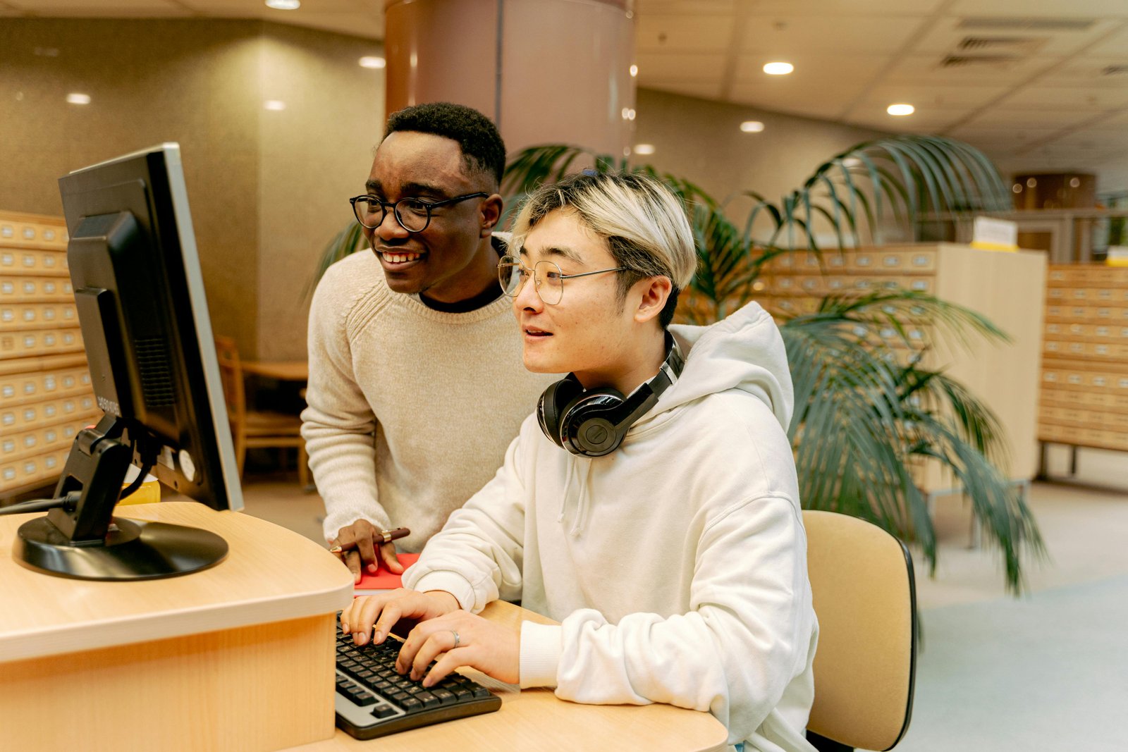 Two young men looking at a computer screen, smiling as though they are happy working together