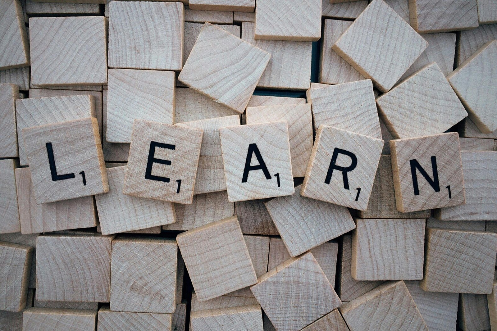 A pile of Scrabble tiles, with 5 of them turned over to reveal the word, 'Learn'